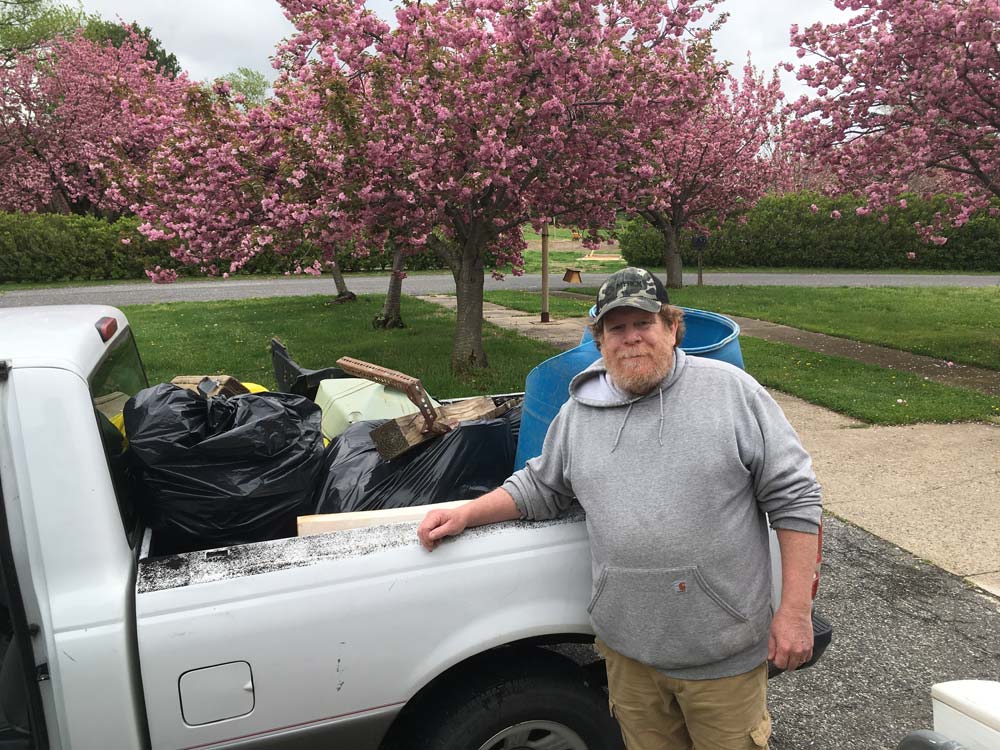 Man standing infront of white pickup truck truckbed with trash bags