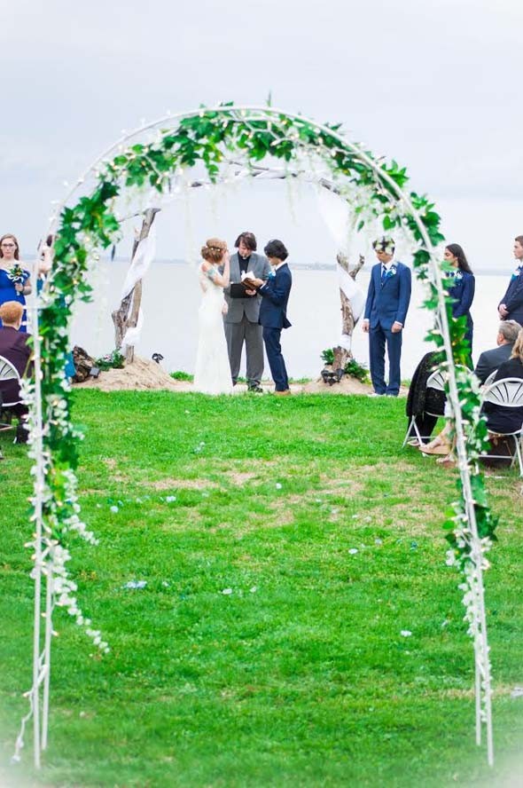 Outdoor wedding, bright green grass, bride groom and priest under manor