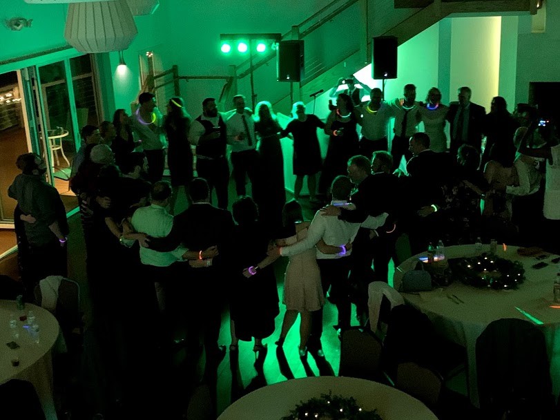 Green glowing lights in reception room, people linked arms in circle