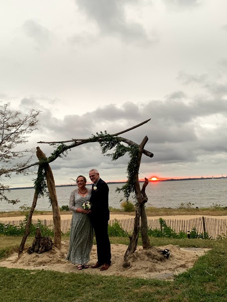 Bride and groom standing under manor on sand with sun setting