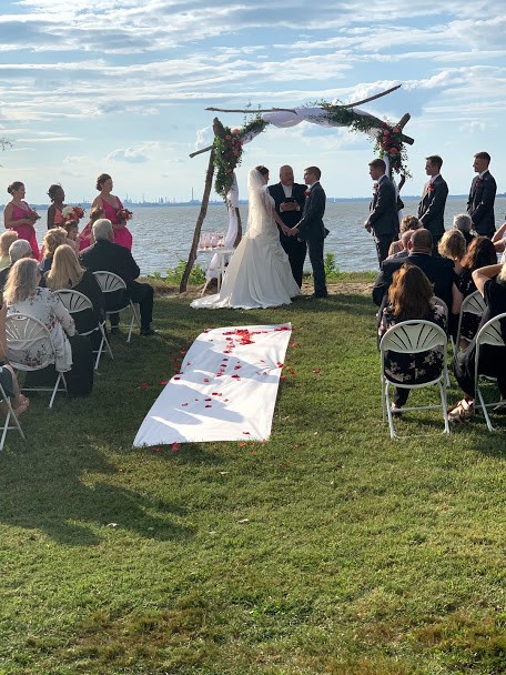 Rose petals on white cloth in aisle of outdoor wedding