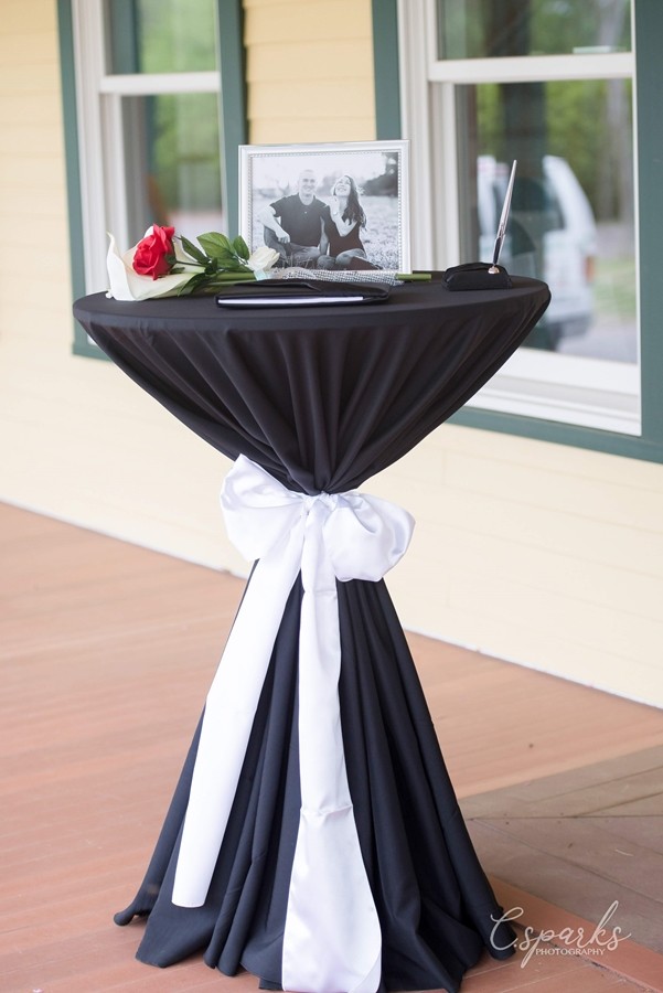 Tall table with black tablecloth with pic of couple on it
