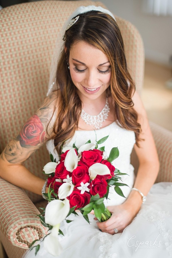 Bride sitting down holding red and white flowers