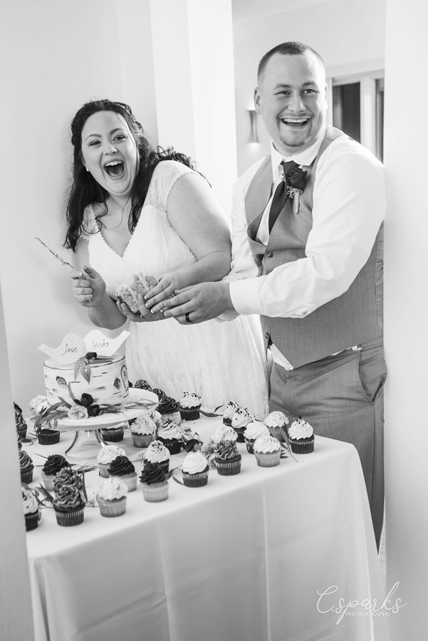 Black and white photo of bride and groom cutting the cake