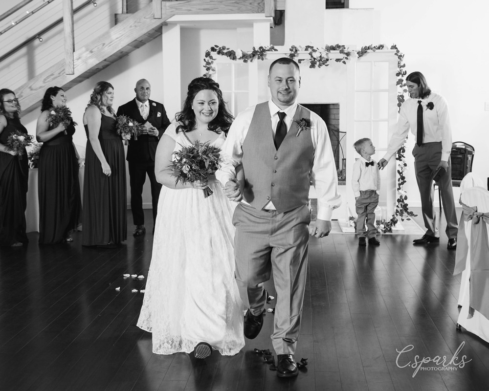 Black and white photo of bride and groom in center of ballroom
