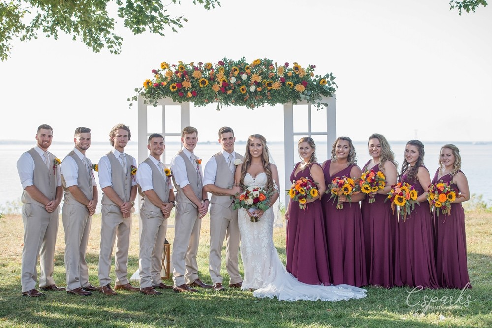 Gride and groom with bridesmaids and groomsmen posing infront of manor