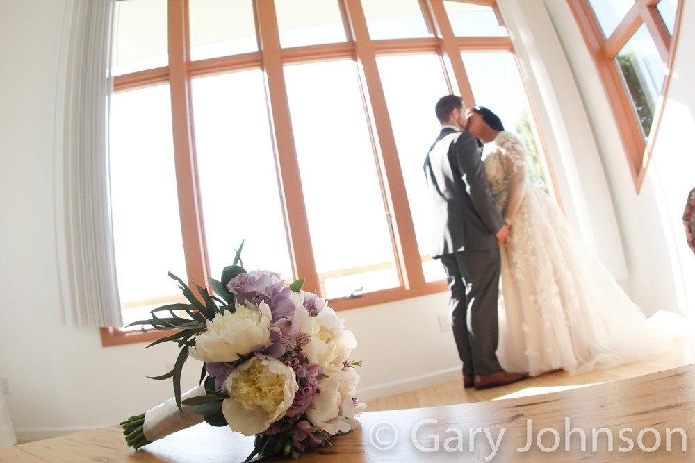 Flowers on table, bride and groom kissing in distance