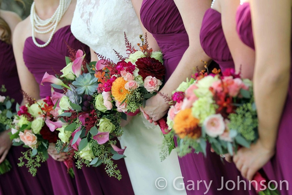 Body-shot of bride standing between bridesmaids holding flowers