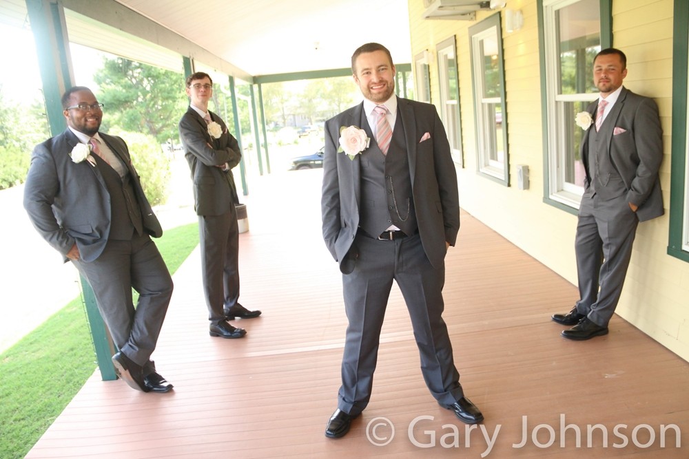 Four men in grey tuxes spread out posing for photo
