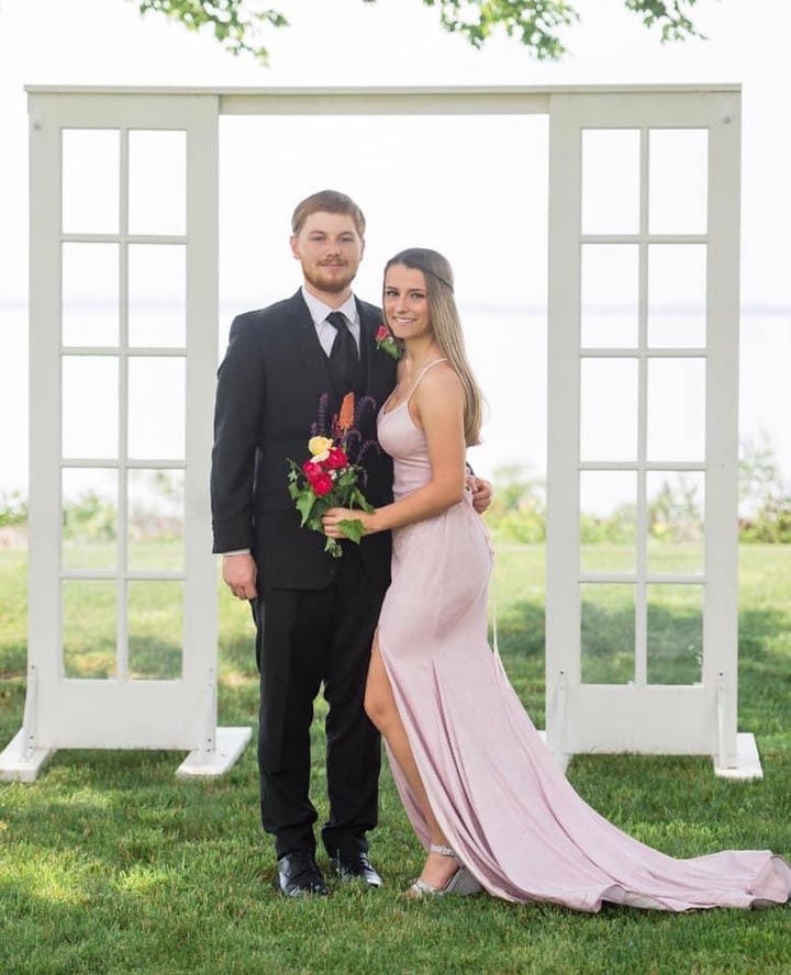 Newly wed couple standing outside in front of windowed backdrop
