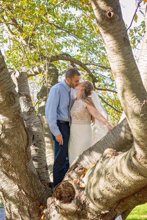 Bride and groom kissing infront of tree