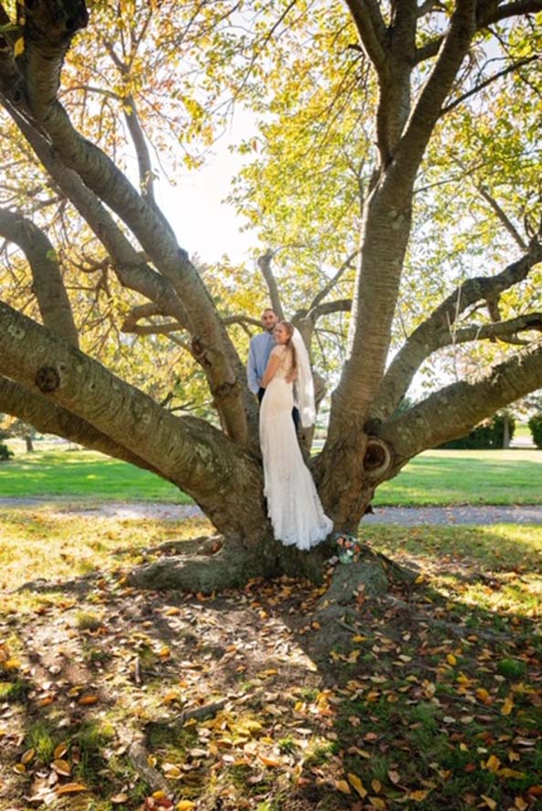 Bride and groom standing infront of large tree