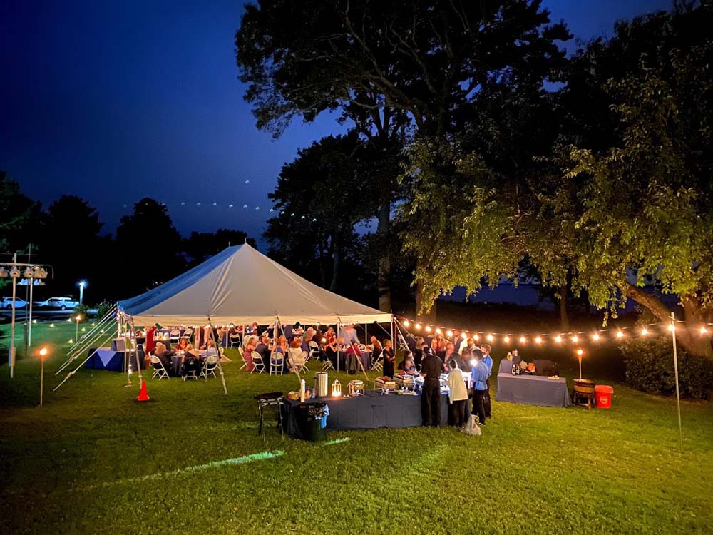 Large event tent outdoors with people sitting under